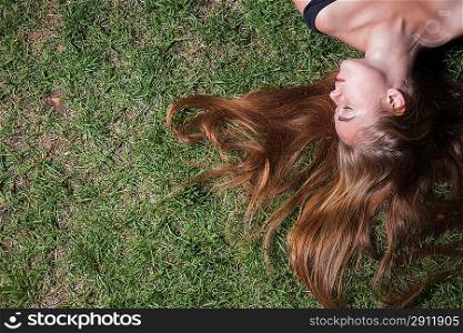 The girl lays on a grass of the meadow. Woman relaxes on the grass. Cute young female lying on grass field at the park.