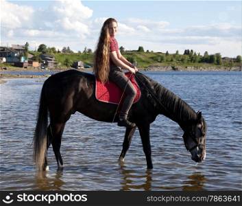 The girl lead a horse to water. Summer landscape.