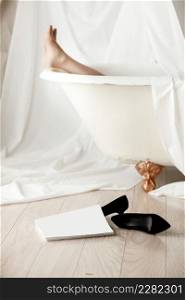 The girl lies in the bath. black high heels and magazine with mock up close to bath.. The girl lies in the bath. black high heels and magazine with mock up close to bath