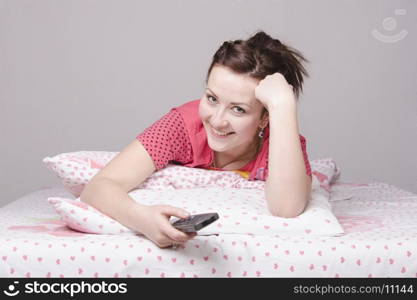 The girl lying in bed and watching TV