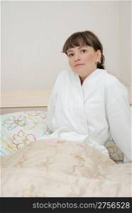 The girl on a bed. It is dressed in a white dressing gown, age of 25 years