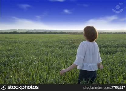 The girl on a meadow. A field of wheat, the contrast sky and the girl looking in a distance