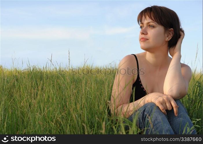 The girl on field. The young girl on green field on a background of the dark blue sky