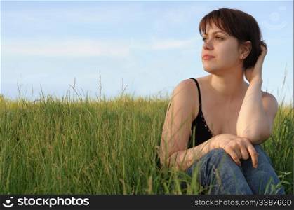 The girl on field. The young girl on green field on a background of the dark blue sky