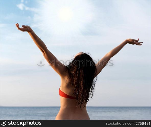 The girl on seacoast with the lifted hands.Greeting sun