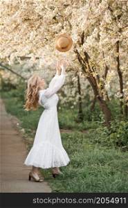 The girl throws her hat in the air in joy.. A girl in a white dress throws a straw hat 2709.