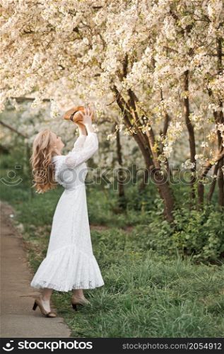 The girl throws her hat in the air in joy.. A girl in a white dress throws a straw hat 2710.