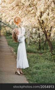 The girl throws her hat in the air in joy.. A girl in a white dress throws a straw hat 2711.