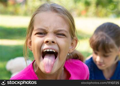 The girl turned and funny shows a long tongue