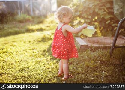 the girl walks in the yard with a leaf in her hand