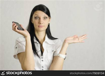 The girl was very surprised after talking on the phone. She spread her hands to the side, keeping in the right hand of the phone and widened her eyes. There is a place under the labels and advertising.