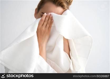 The girl wipes her face with a white terry towel.. The girl wipes her face with a terry towel.