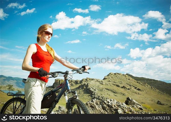 The girl with a bicycle against mountains