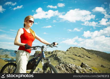 The girl with a bicycle against mountains