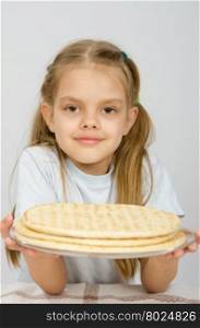 The girl with a slight smile holding a pizza crust on a plate