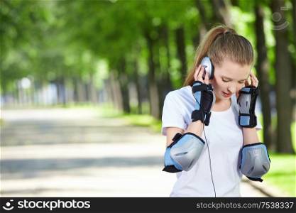 The girl with ear-phones against green trees