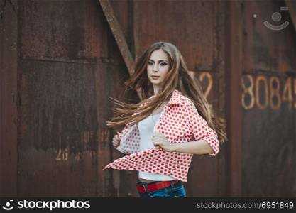 The girl with long hair about brick the container in port.. Portrait of the girl in a shirt and jeans 1599.