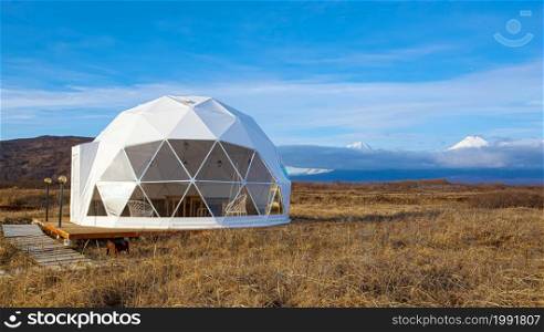 The Glamping house in summer and volcano, rural landscape, tent houses in Kamchatka peninsula. Selective focus.. Glamping house in summer and volcano, rural landscape, tent houses in Kamchatka peninsula. Selective focus.