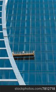 The glass wall of office building with windows and construction lift