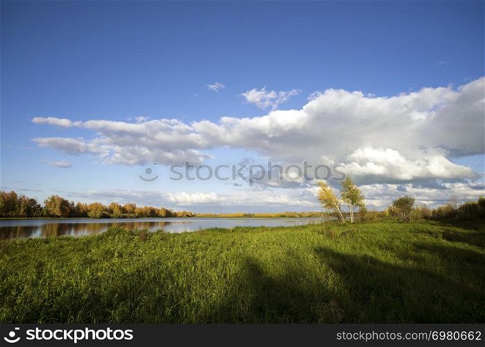 The Golden autumn landscape in Western Siberia.. Clouds over the lake.