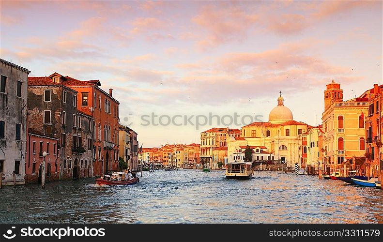 The Grand Canal in Venice early in the morning, with barges delivering goods and a Vaporetto ferry-bus taking passengers to their destinations.