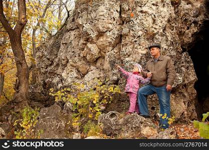 The grandfather and grand daughter are near the cavern