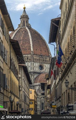 The great dome of the Duomo (Cattedrale di Santa Maria del Fiore) seen from a side street off Piazza Duomo in Florence in Tuscany, Italy. Construction began in 1296 in the Gothic style to the design of Arnolfo di Cambio and completed structurally in 1436 with the dome engineered by Filippo Brunelleschi. A UNESCO World Heritage Site.