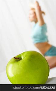 The green apple in the foreground, on a background the young girl goes in for sports. Healthy way of life