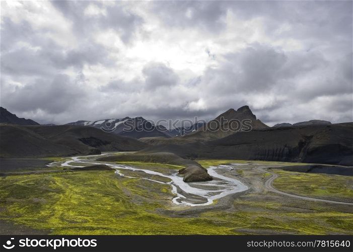 The green river bedding amongst the volcanic mountain ridges in the Landmannalaugar region Iceland on an overcast day