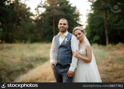 the groom and the bride are walking in the forest on a bright day