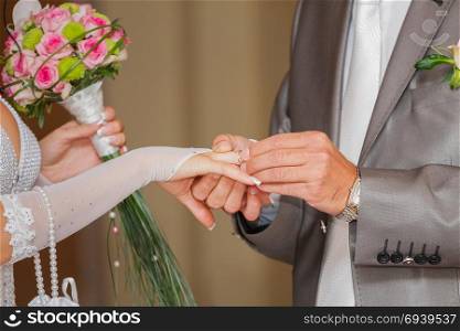 The groom has put on an engagement ring on a finger of the bride. Wedding ceremony, exchange of rings, wearing wedding ring