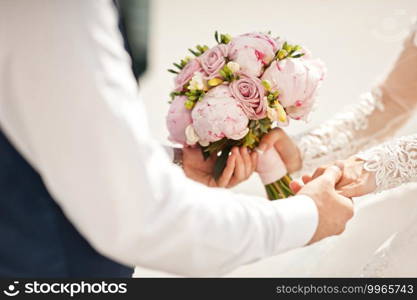 The groom holds the brides hands with a wedding pink bouquet in his hands.. The bride and groom stand opposite each other and hold hands 2671.