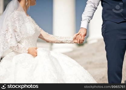 The groom holds the brides hands with a wedding pink bouquet in his hands.. The groom holds the brides palm in his hand 2670.