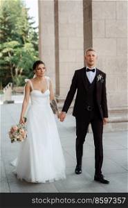 the groom in a brown suit and the bride in a white dress in an urban atmosphere