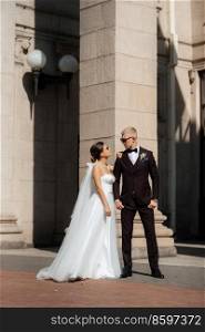 the groom in a brown suit and the bride in a white dress in an urban atmosphere