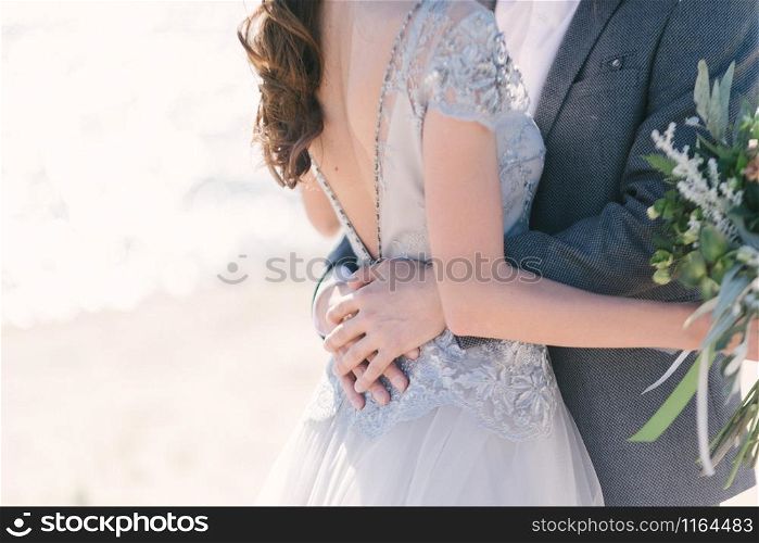 The groom in a suit hugs the bride in a wedding dress close up. The groom in a suit hugs the bride in a wedding dress