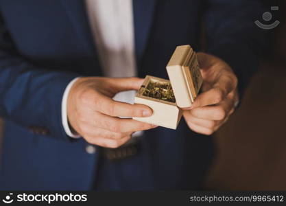 The groom is holding a beautiful wooden box with gold wedding rings.. In the hands of the groom is a wooden box with gold wedding rings 2599.