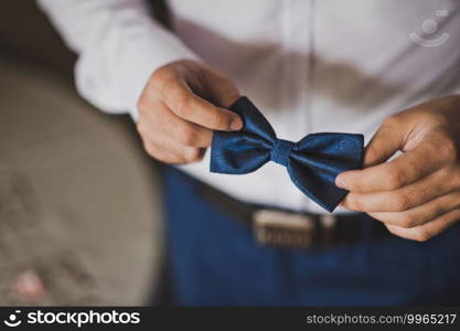 The groom is holding a blue bow tie with patterns.. Blue bow tie with patterns in the hands of the groom 2598.