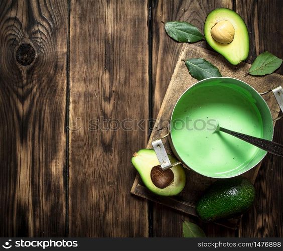 The guacamole and greens on the Board. On wooden background.. The guacamole and greens on the Board