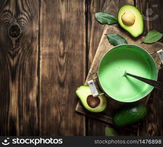 The guacamole and greens on the Board. On wooden background.. The guacamole and greens on the Board