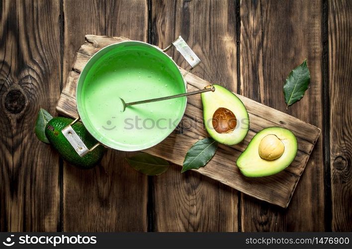 The guacamole and greens on the Board. On wooden background.. The guacamole and greens on the Board