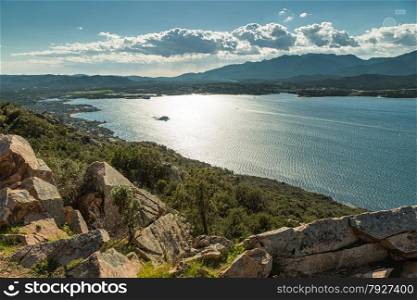 The gulf of Porto-Vecchio in the south of the island of Corsica with the town and hills in the background and rocks and maquis in the foreground