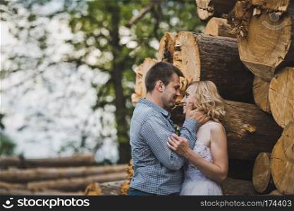 The guy and the girl walk among fire wood.. Walk of a newly-married couple about logs 3242.