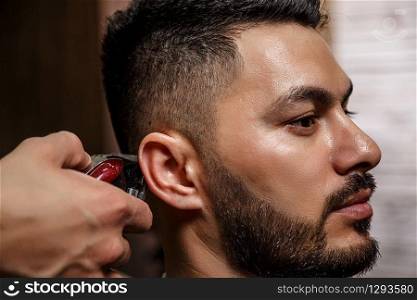 the guy is a dark-haired Asian Indian appearance on a haircut in a barbershop . cinematic image