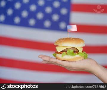 The hamburger piece is placed on the palm of the hand, with a backdrop of the US flag.