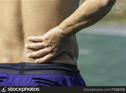 The hand grips the waist that inflammation from a sports injury.