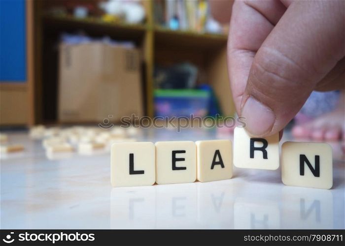 The hand holds a cube with R letters from learn word. Learn word