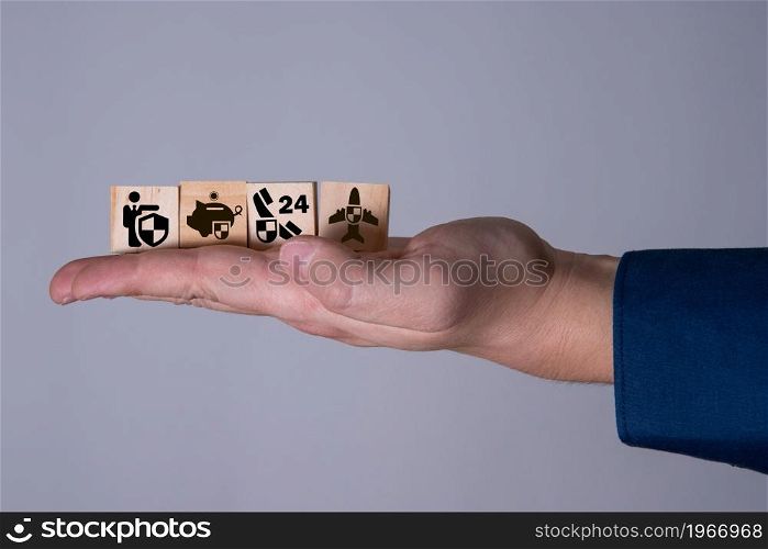 The hand holds wooden cubes with insurance icons. The concept of life insurance and medicine.. The hand holds wooden cubes with insurance icons.