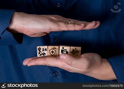 The hand holds wooden cubes with insurance icons. The concept of life insurance and medicine.. The hand holds wooden cubes with insurance icons.