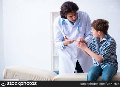The hand injured boy visiting young male doctor. Hand injured boy visiting young male doctor